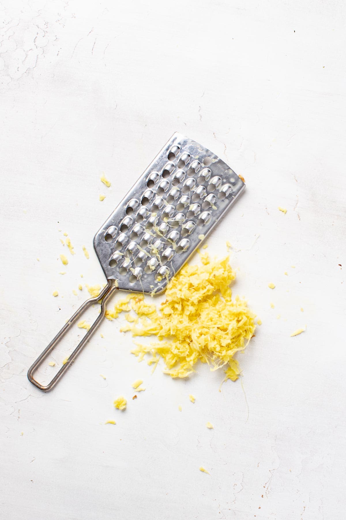 Grated ginger next to a cheese grater.