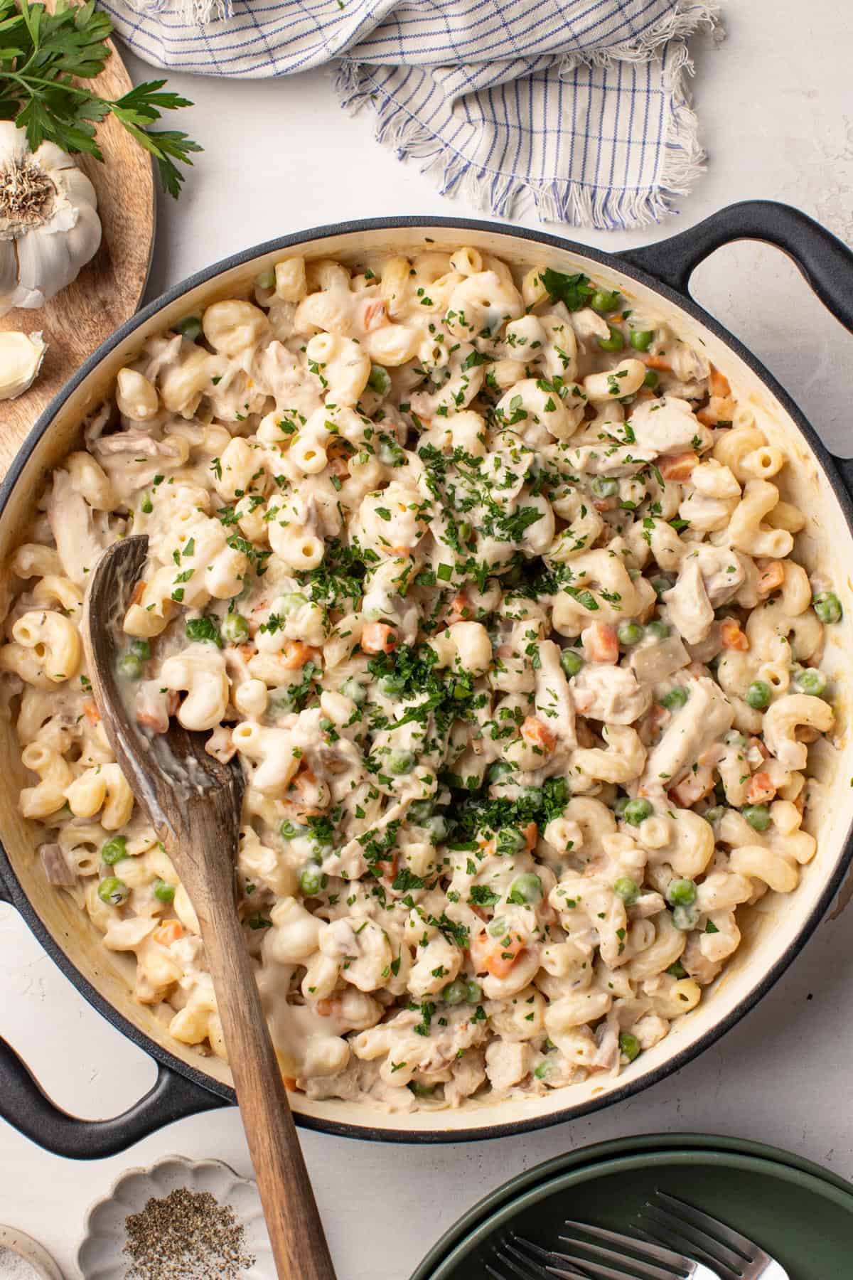 Chicken pot pie pasta in a large pot with a wood spoon dipped into the pasta.