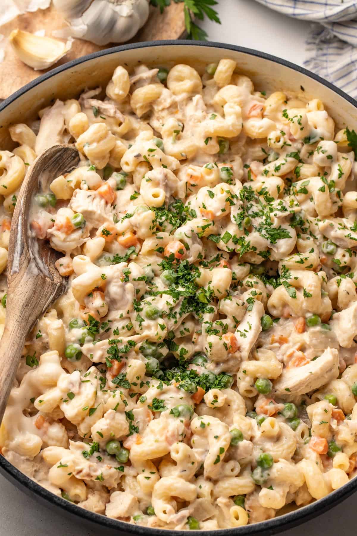 Creamy pasta with rotisserie chicken and veggies in a large cast iron pot.