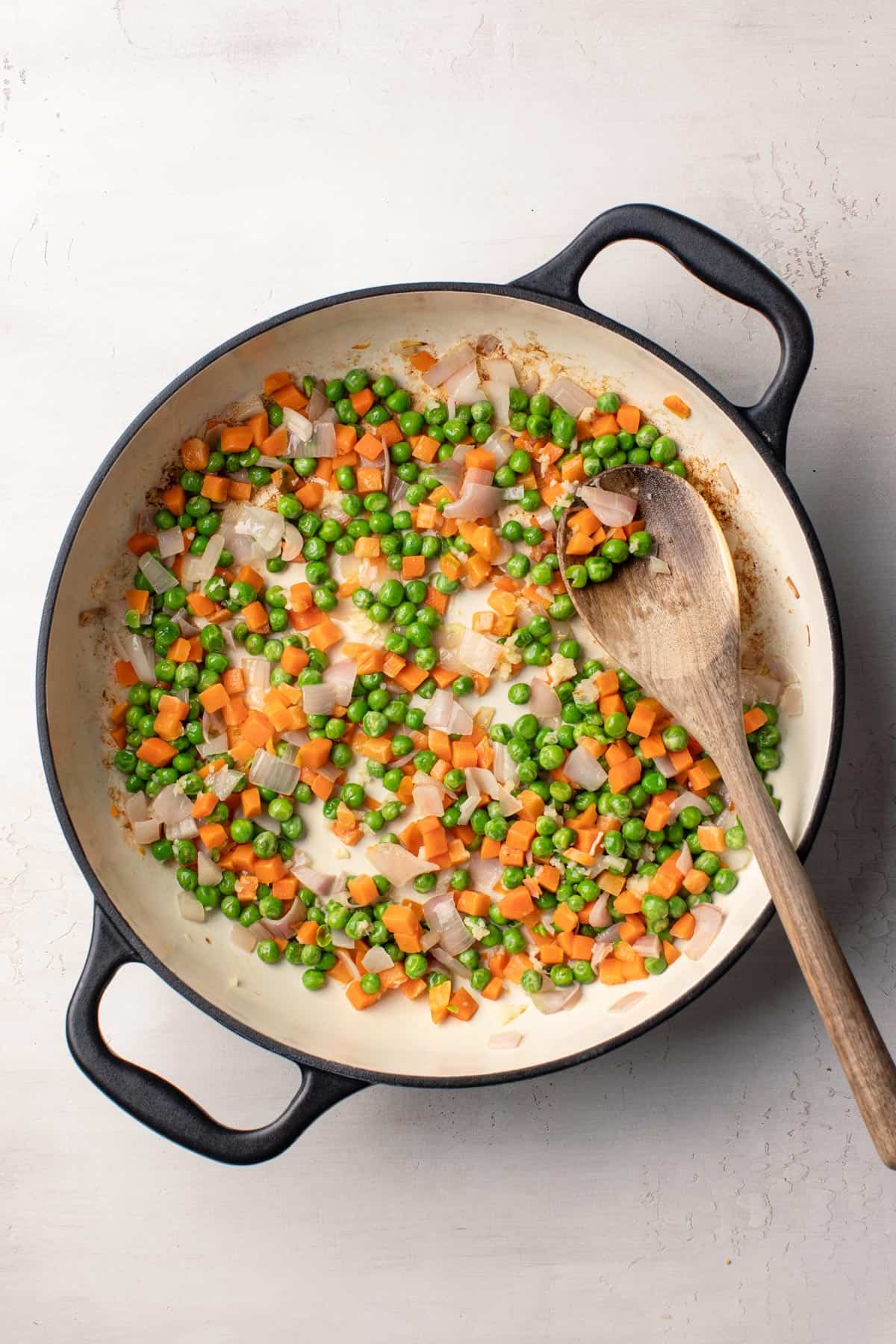 Cooking frozen peas and carrots in a saucepan with shallots and butter.