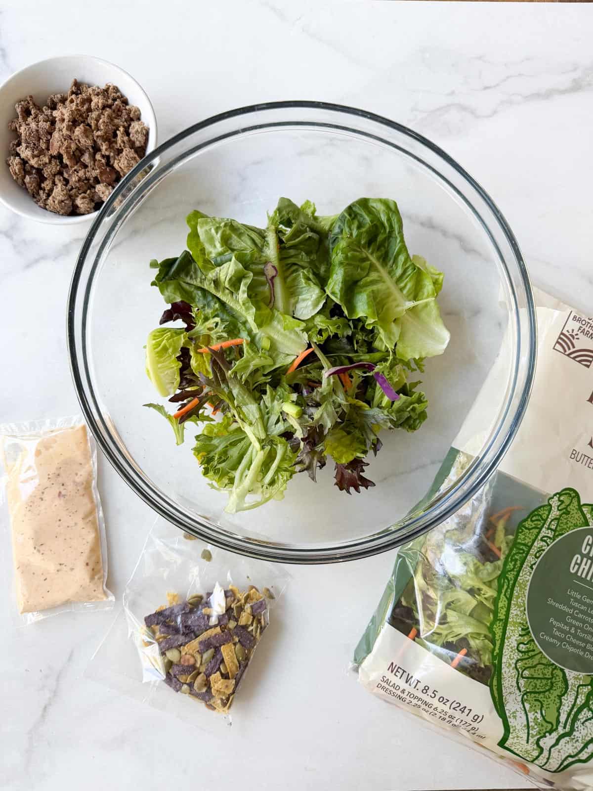 Ingredients for a ground beef salad on a white table.