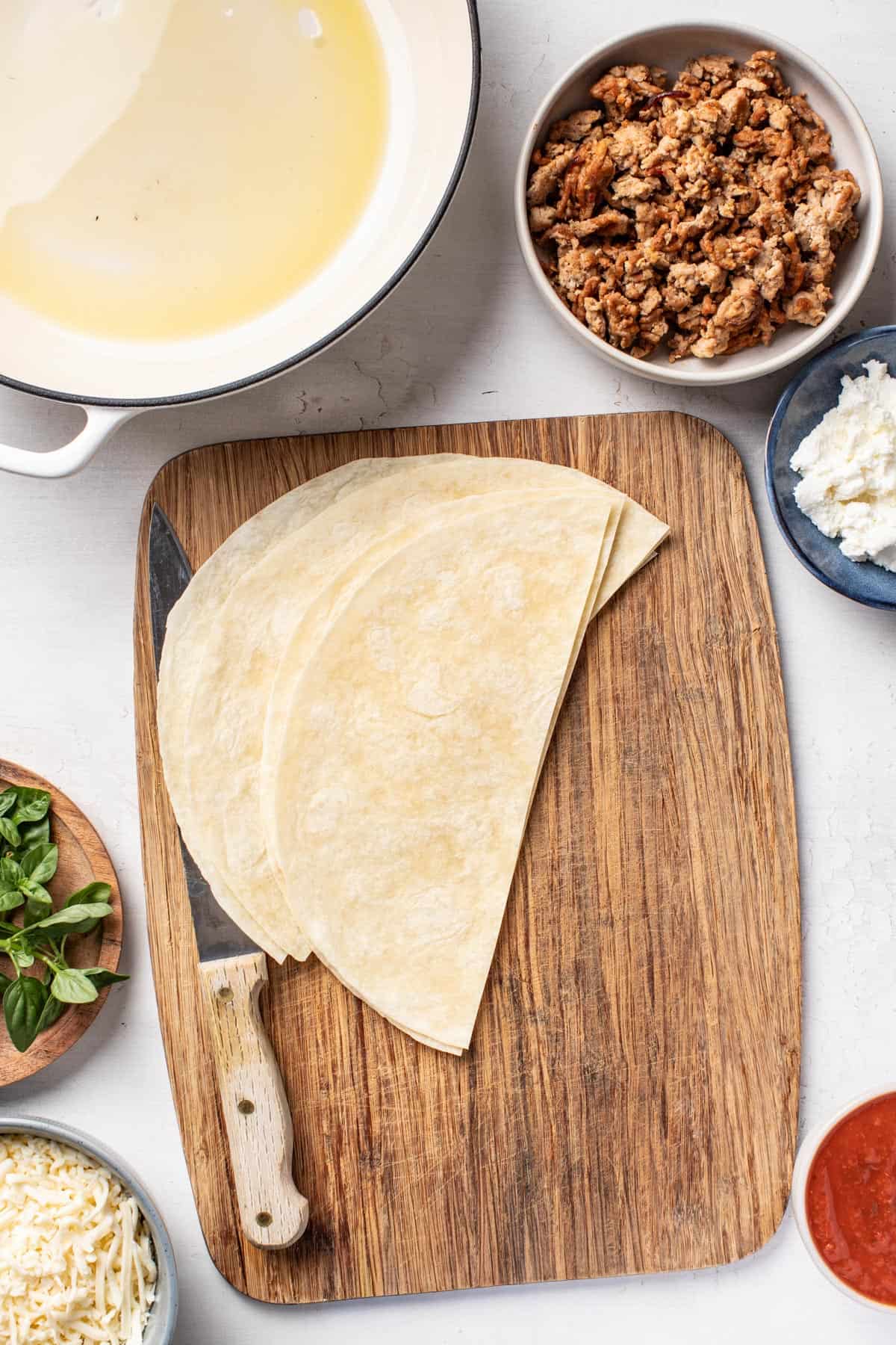 Tortillas sliced in half on a cutting board.