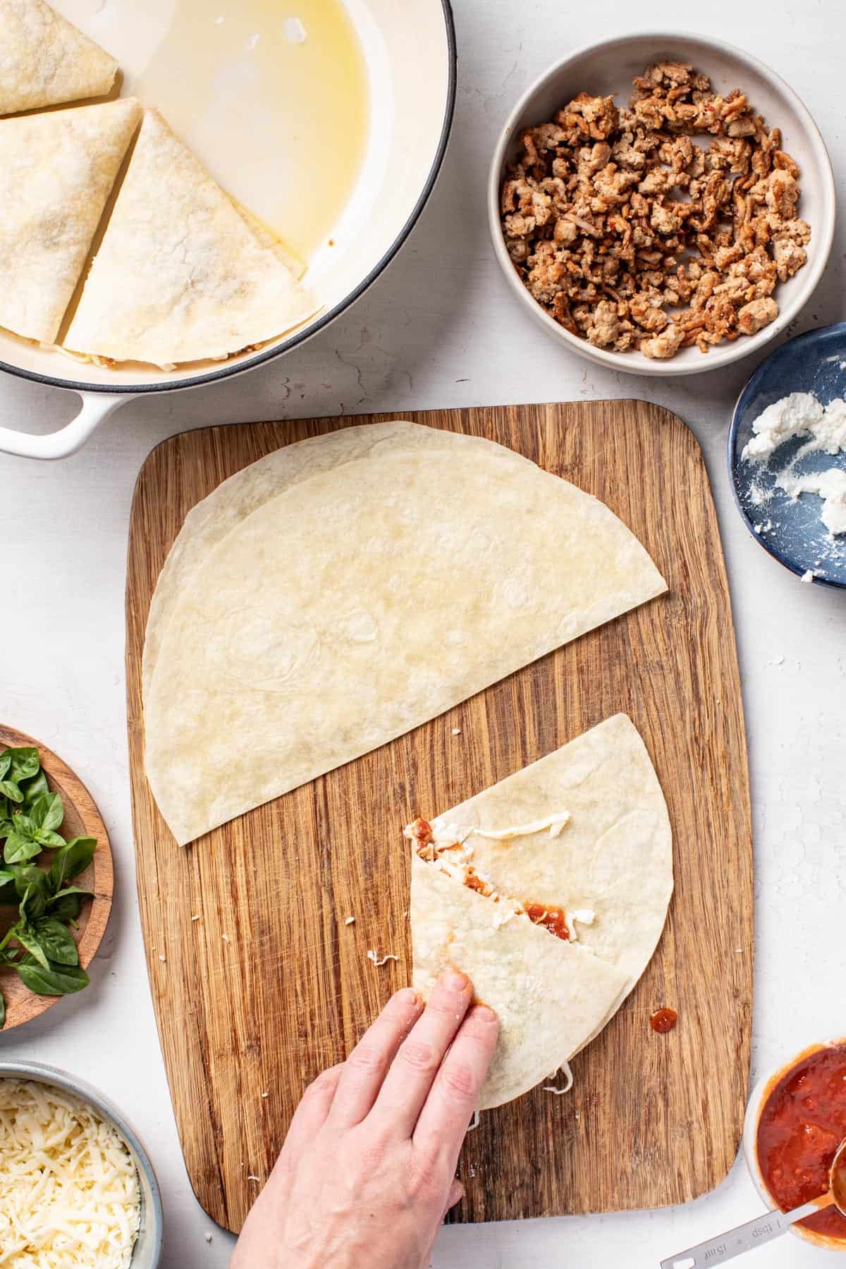 Folding the sides of the tortilla over the pizza filling to create a triangle.
